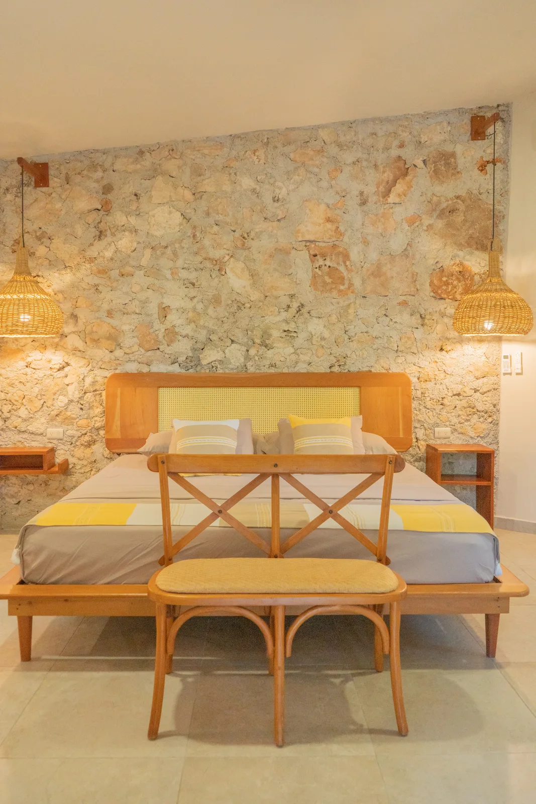 Bungalow bedroom with stone wall and wicker pendants
