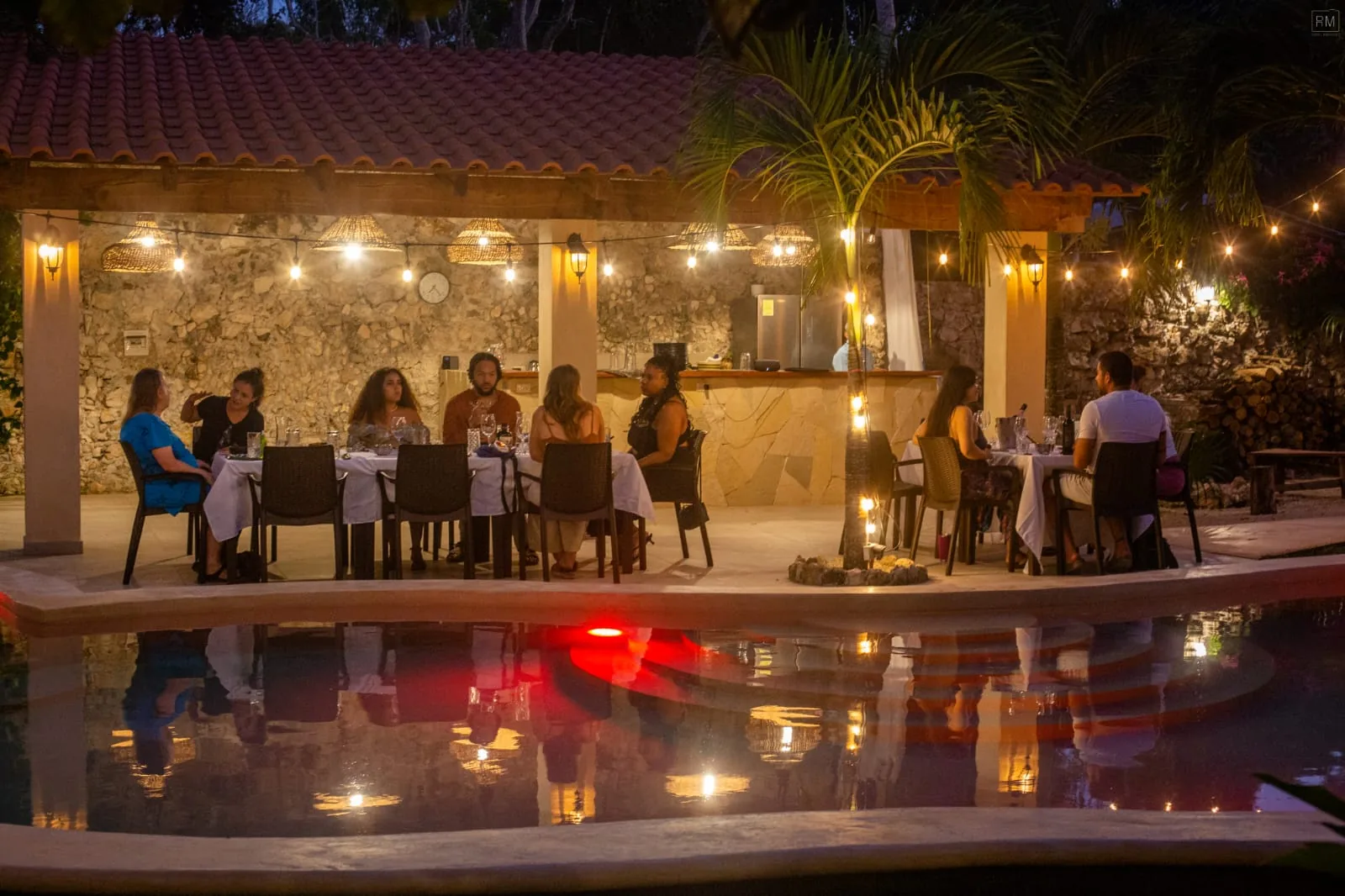 Evening dinner under the palapa with string lights and pool reflection